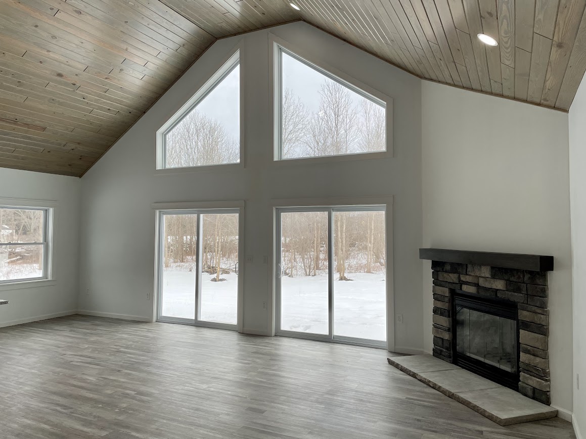 Modular home chalet with vaulted ceiling, fireplace, open concept, rustic wood planking on the ceiling and LVP flooring