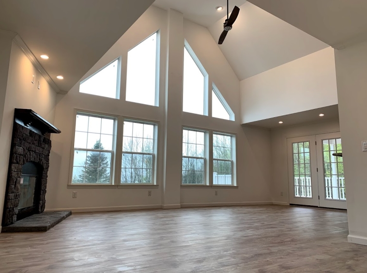 Open concept modular home chalet with vaulted ceiling, large windows, and fireplace with kitchen brings the family together in one space for your vacation cottage or primary home.
